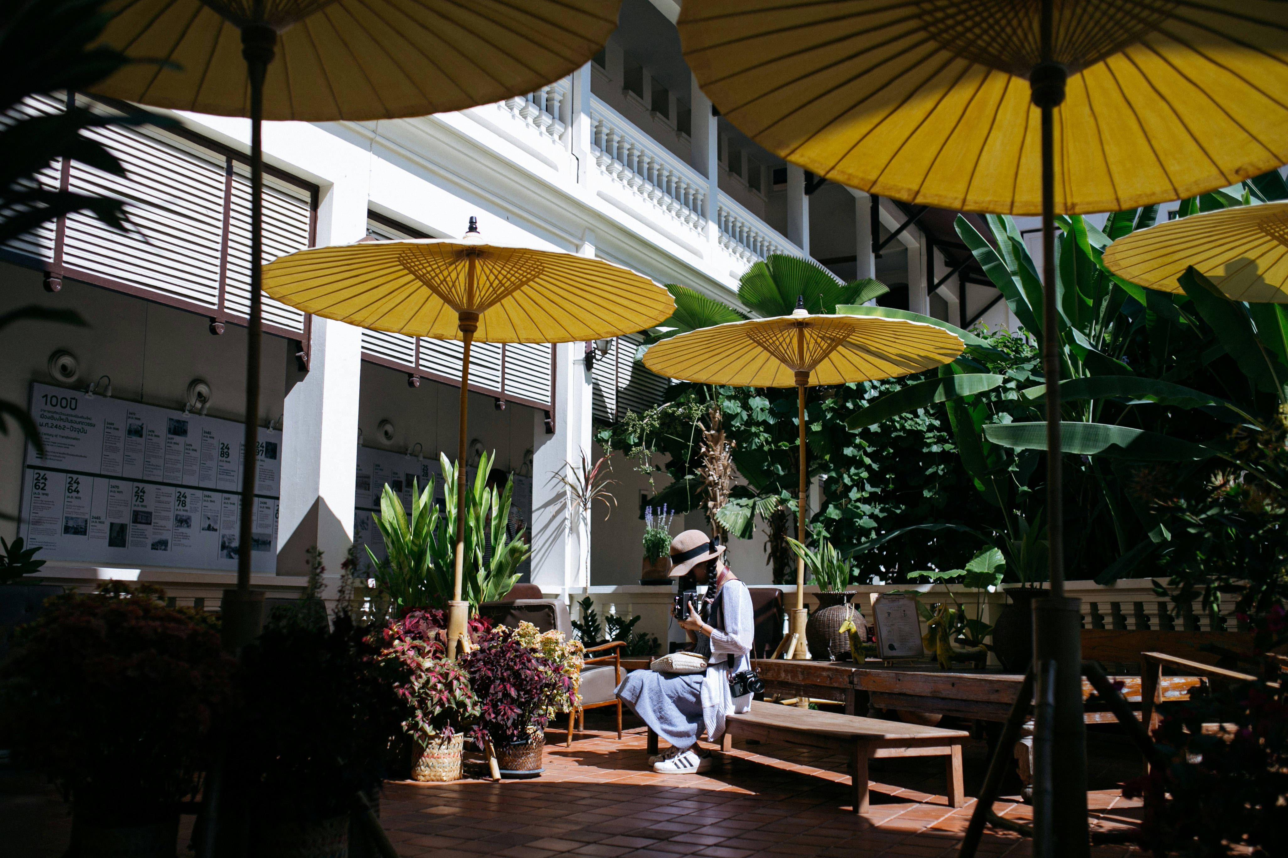 man in blue shirt sitting on brown wooden chair under yellow umbrella during daytime